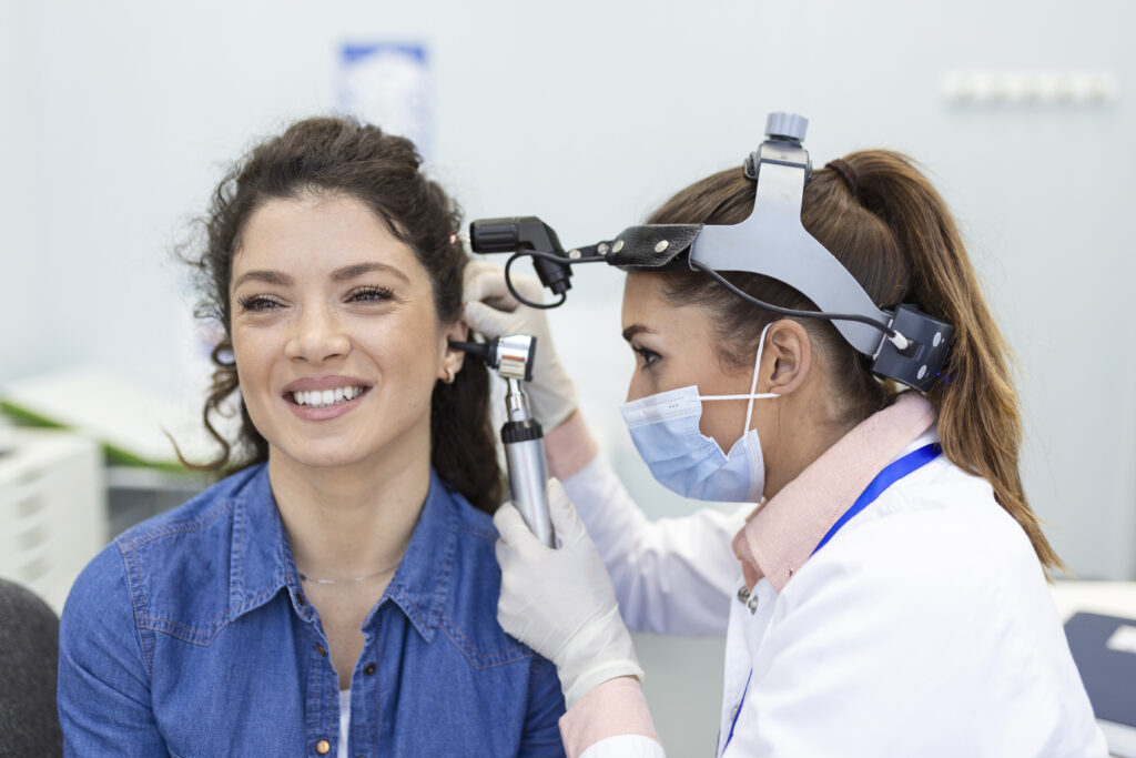 hearing exam. otolaryngologist doctor checking woman's ear using otoscope or auriscope at medical clinic.